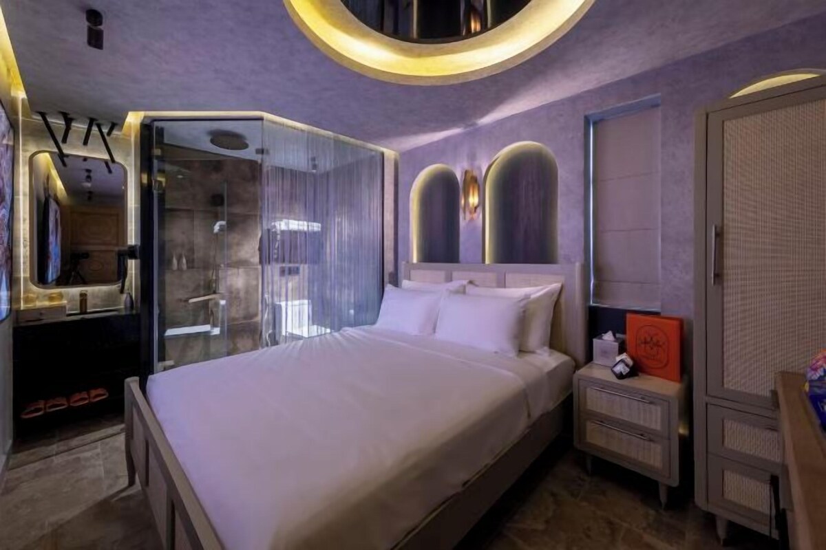 Une chambre moderne dotée d’un grand lit, d’un dressing et d’une douche à parois de verre.