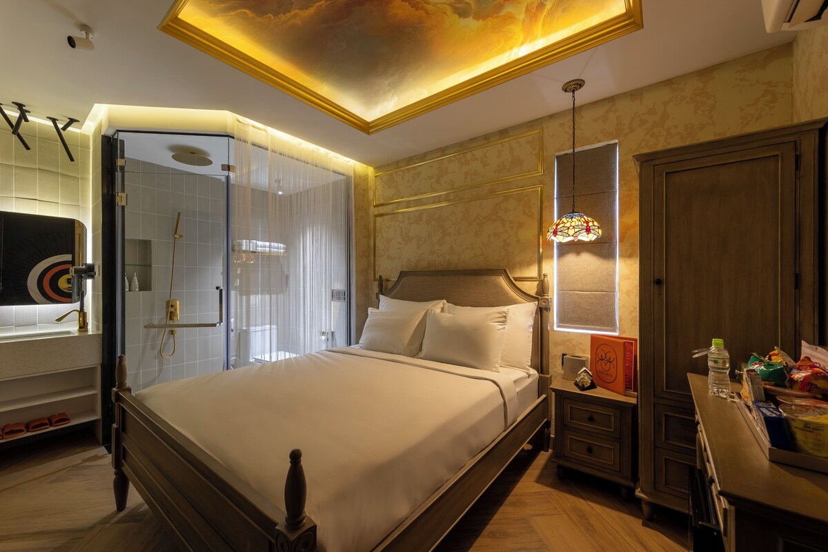 A spacious bedroom with a large bed, a walk-in closet, and a shower area.