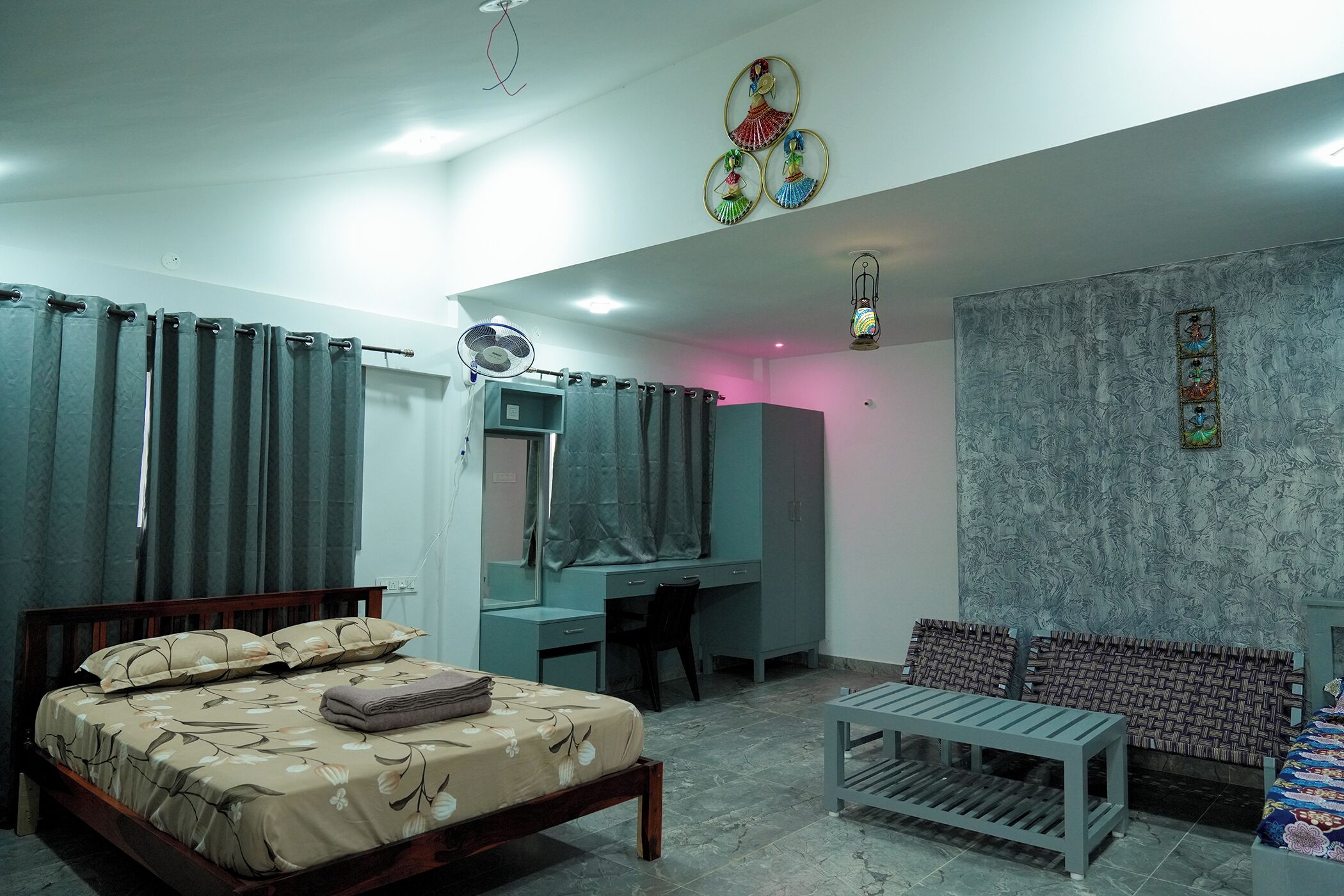 A bedroom with a bed, desk, and seating area.