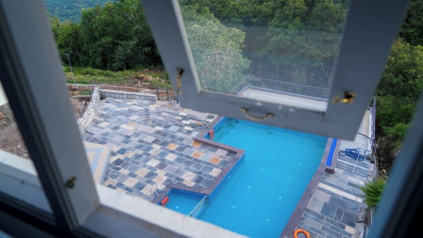 A pool with a tiled deck and a view of a forested area. - BlueHill Lotus Holistic Wellness Village (Sirumalai)