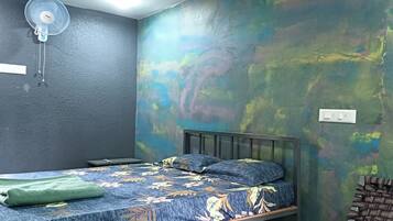 A room with a bed, a wall-mounted fan, and a colorful abstract wall mural.