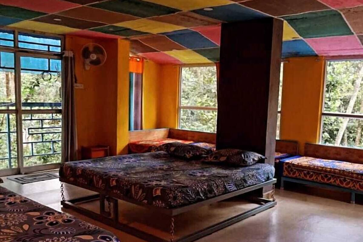 Una habitació amb un llit, una banca i una finestra amb vista a vegetació.