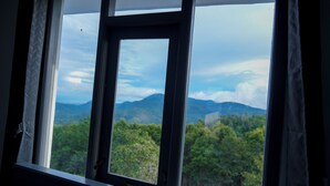 A window with a view of a forested mountain range. - BlueHill Lotus Holistic Wellness Village (Sirumalai)