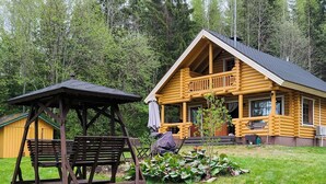 Une cabane en rondins avec un porche, une balançoire en bois et un espace salon abrité.