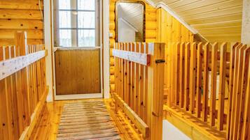 Un interno in legno con una porta centrale che dà su una finestra, affiancata da ringhiere in legno e un tappeto a righe.