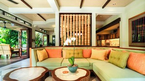 A modern living room with a green sofa, wooden coffee tables, and a potted orchid. - The Ubāri Bali (Ubud)