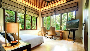 A bedroom with a bed, desk, chairs, and a painting. - The Ubāri Bali (Ubud)