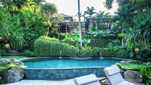 A pool surrounded by lush greenery and wooden lounge chairs. - The Ubāri Bali (Ubud)