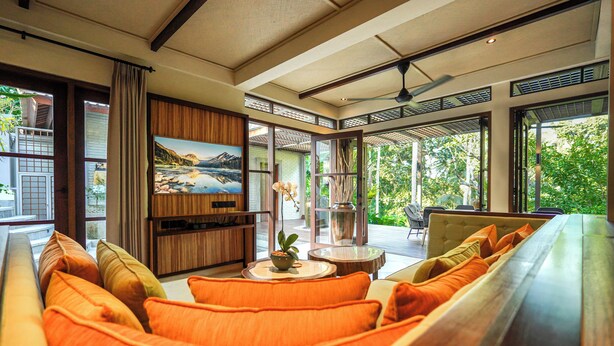 A modern living room with a sofa, a TV, and a view of greenery outside. - The Ubāri Bali (Ubud)