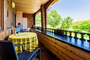 A wooden deck with a table and chairs, overlooking a green landscape.