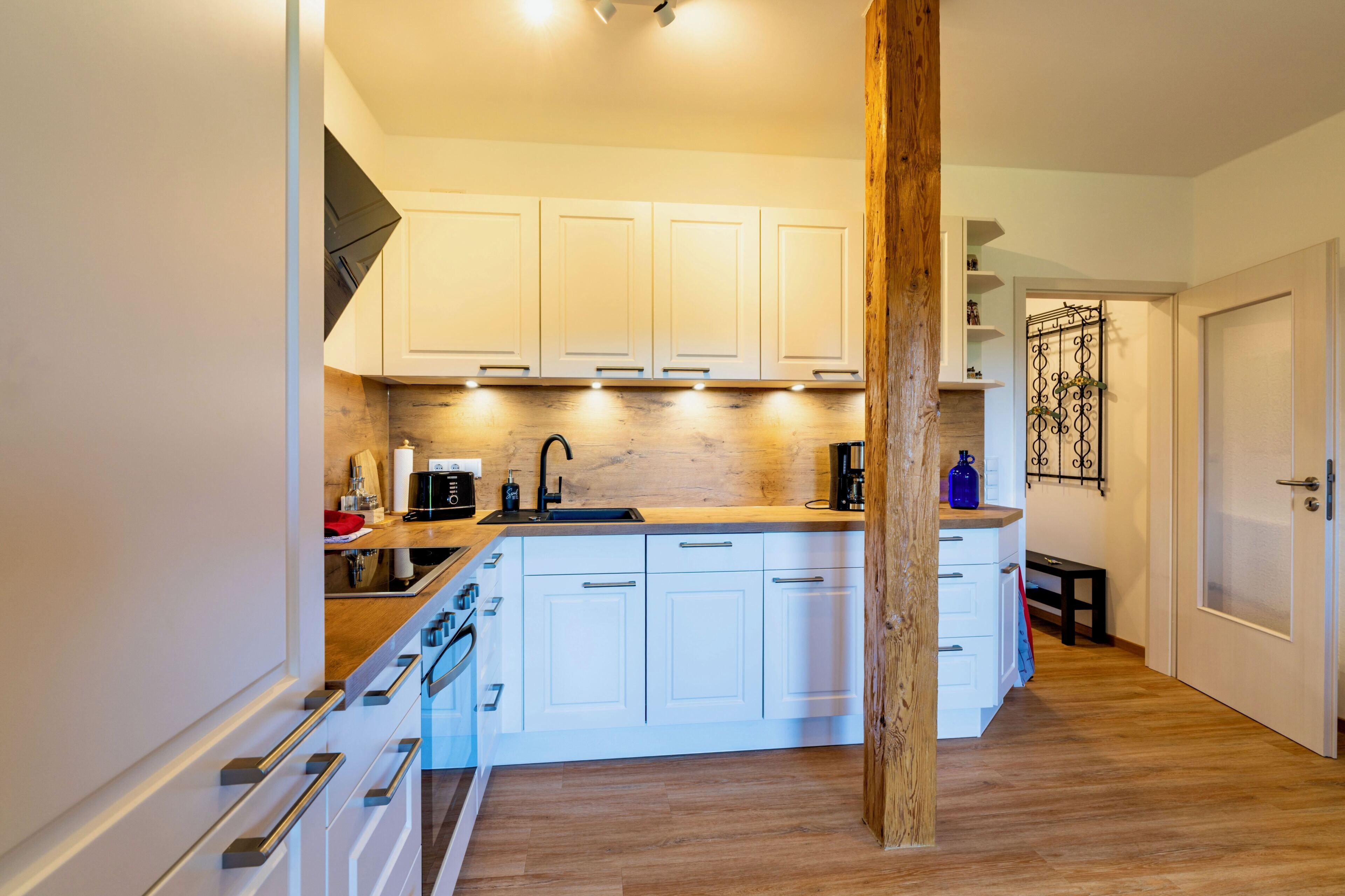 Een moderne keuken met witte kasten, een houten eiland en een inbouwoven.