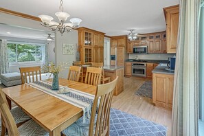 Enjoy meals in the well-appointed kitchen and dining area, featuring a central island, cabinetry, and a chandelier.