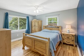 Relax in this serene bedroom with a large bed, ceiling fan, and comfortable seating area.