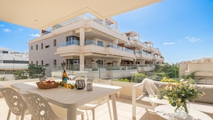 Eine moderne Wohnung mit einem Balkon, möbliert mit einem Tisch, Stühlen und einer Blumenvase.