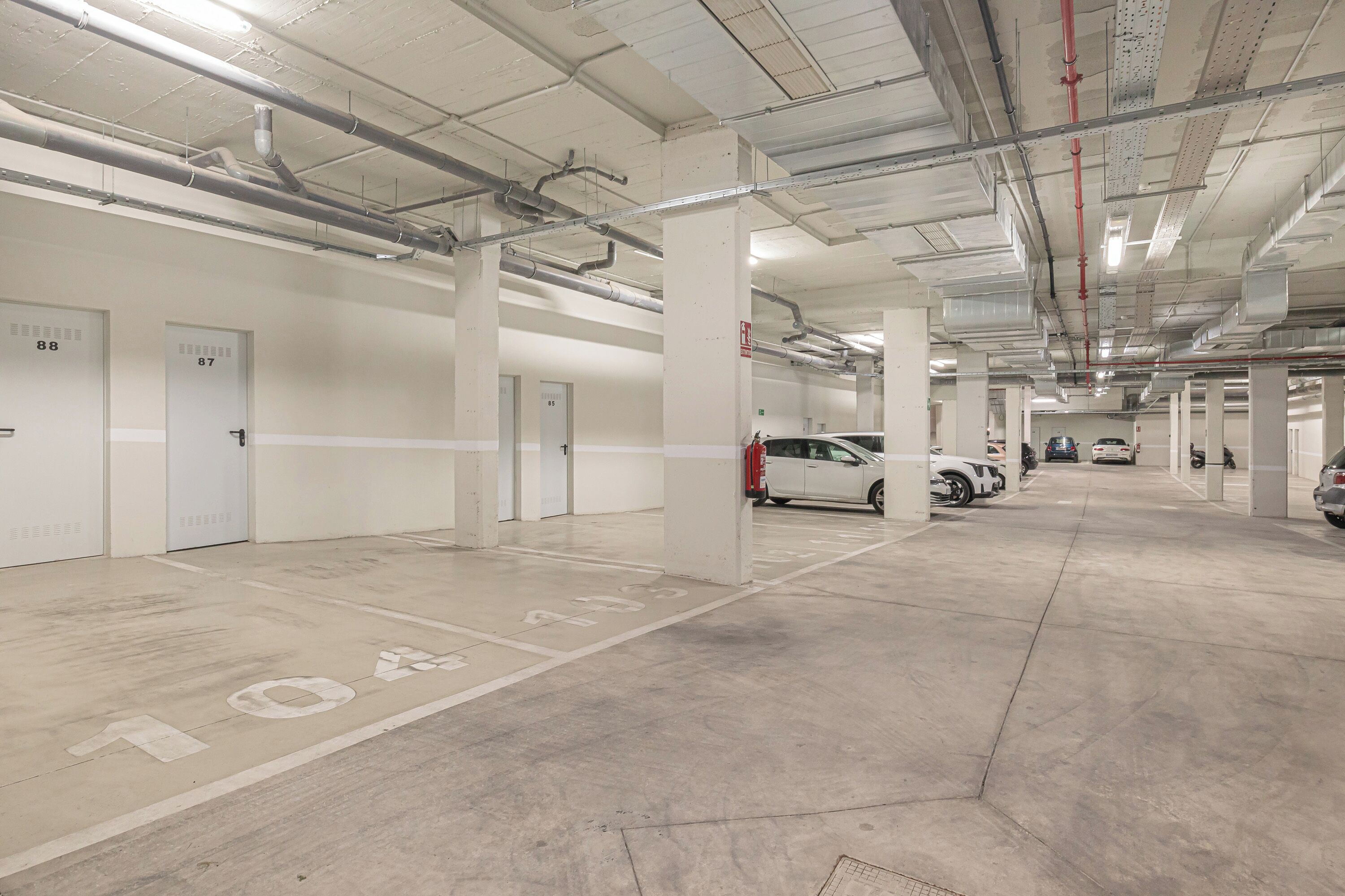 A multi-level parking garage with concrete floors, white walls, and numbered parking bays.