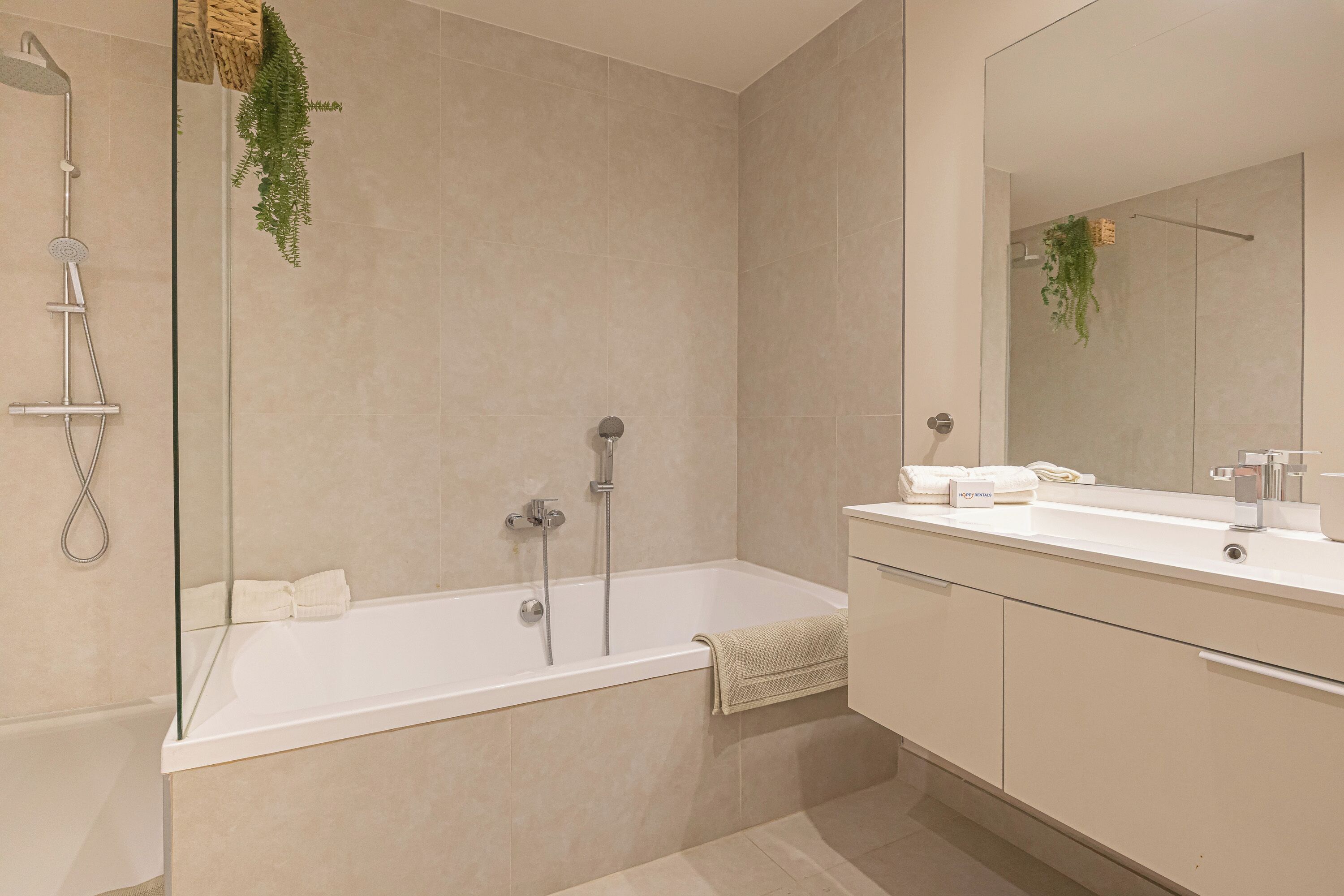 Un baño moderno con bañera, ducha y un espejo grande.