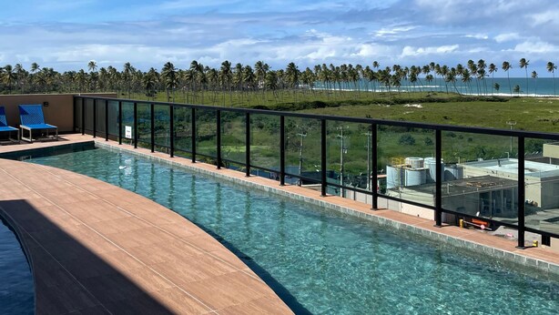 A swimming pool with a clear view of the ocean and palm trees in the background.