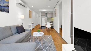 A modern living room with a grey sofa, a small white table with a plant, and a fireplace.