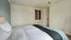Une chambre à coucher avec un lit, une porte et une petite fenêtre.