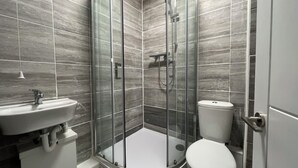 Une salle de bain moderne avec une douche à parois de verre, un lavabo blanc et des toilettes.