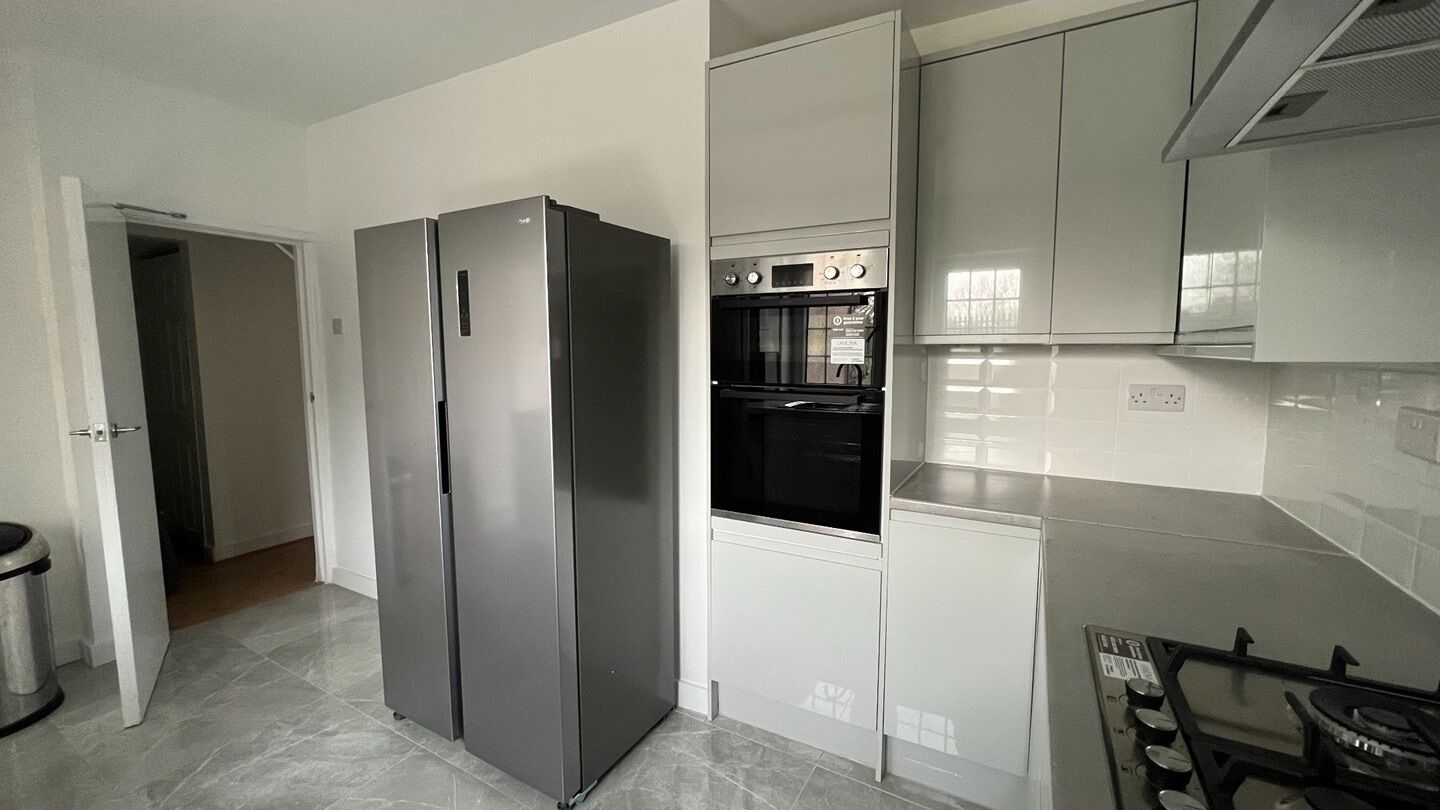 A modern kitchen with stainless steel appliances, a built-in oven, and white cabinetry.