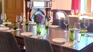 Un comedor con mesas dispuestas para una comida, destacando vasos de vidrio verde y platos blancos.