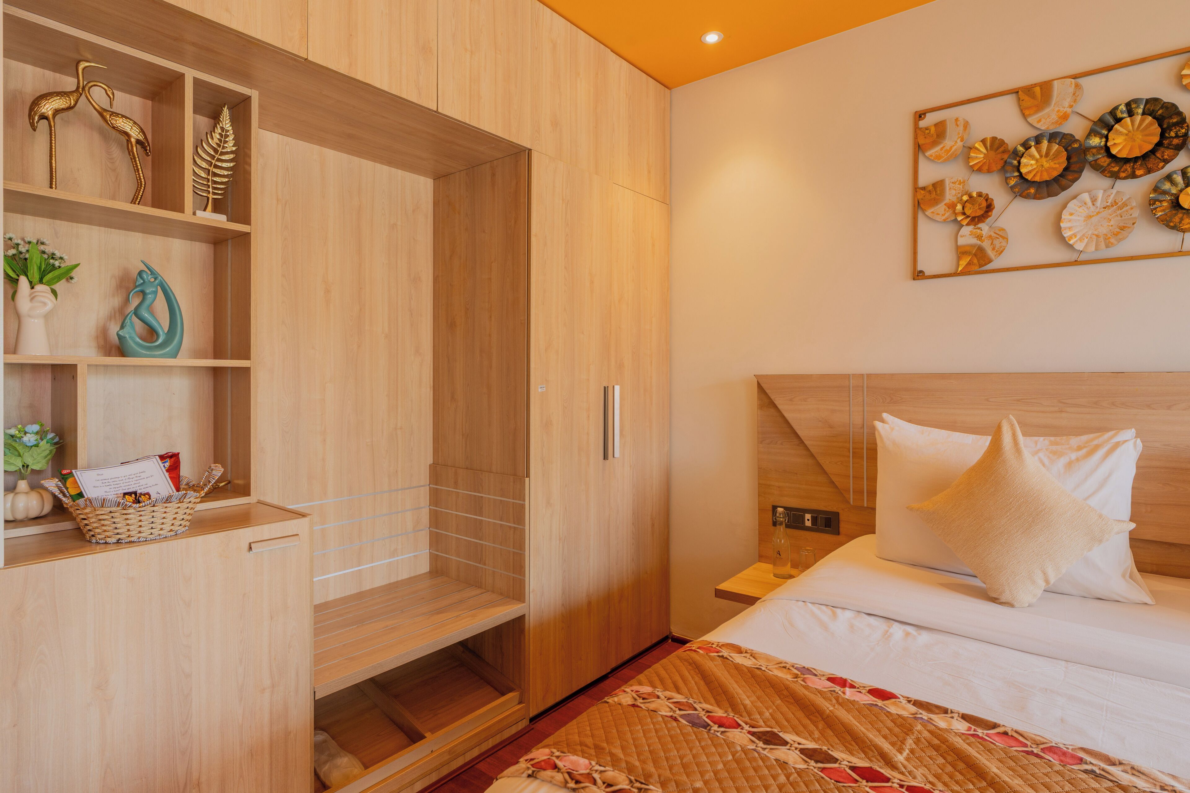 A modern bedroom with a wooden wardrobe, a bed with a quilted cover, and a wall art piece.