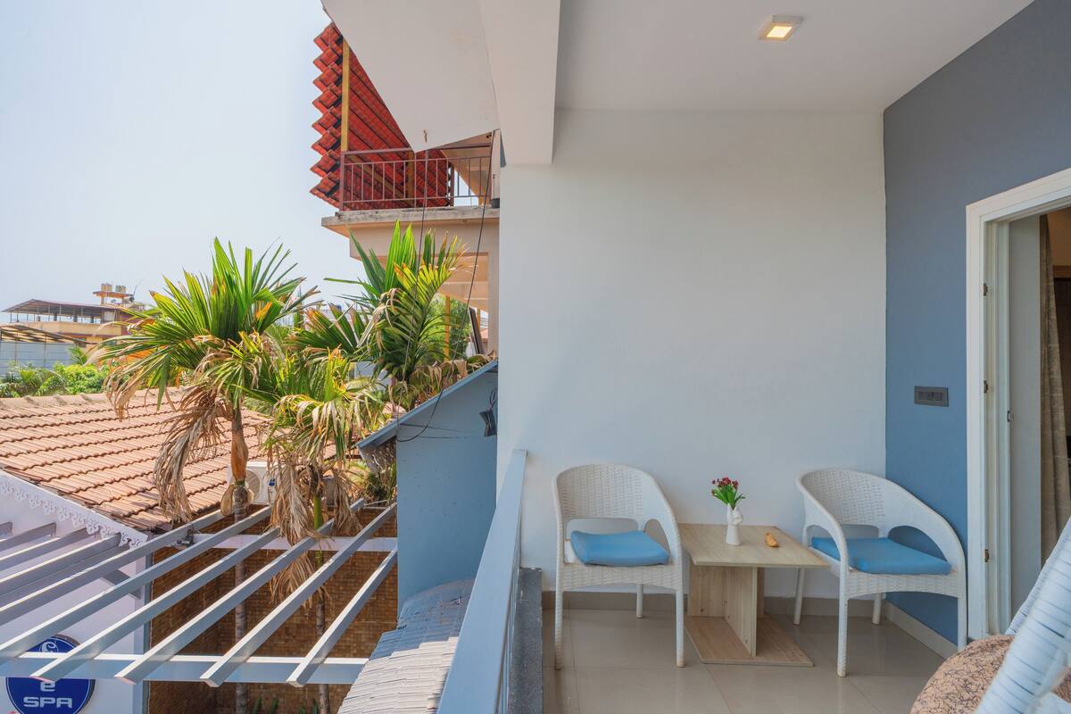 A balcony with a white chair, a small table, and a potted plant.