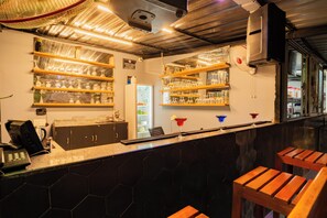 A bar area with shelves of glasses, a refrigerator, and a counter with a phone and a coffee machine. - Alaya Stays Gracias Seaora Retreat (Morjim)