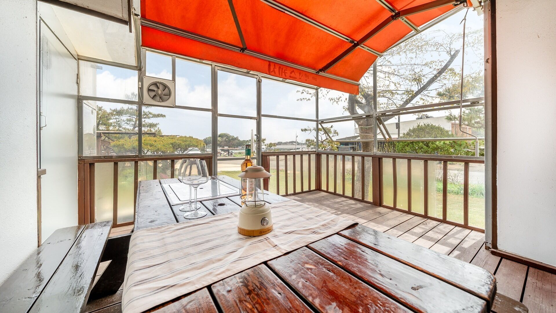A wooden deck with a table, a lantern, and a fan.