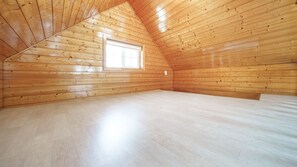 A room with wooden walls and a sloped ceiling, a window, and a light-colored floor. - Daebudo Sketch Pension (Ansan)