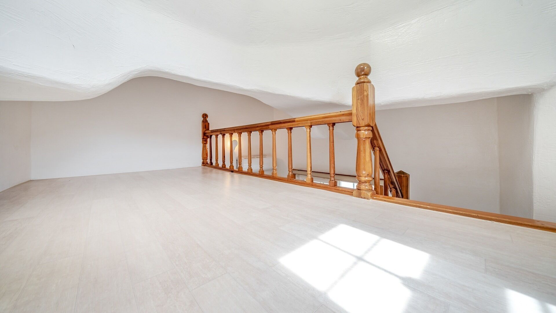 Ein geräumiger Raum mit einer Holztreppe und einer hohen Decke.