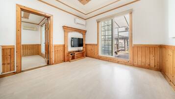 A spacious room with wooden paneling, a large window, and a built-in entertainment unit.