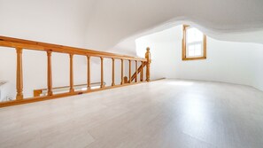 A spacious attic room with a wooden staircase and a skylight.