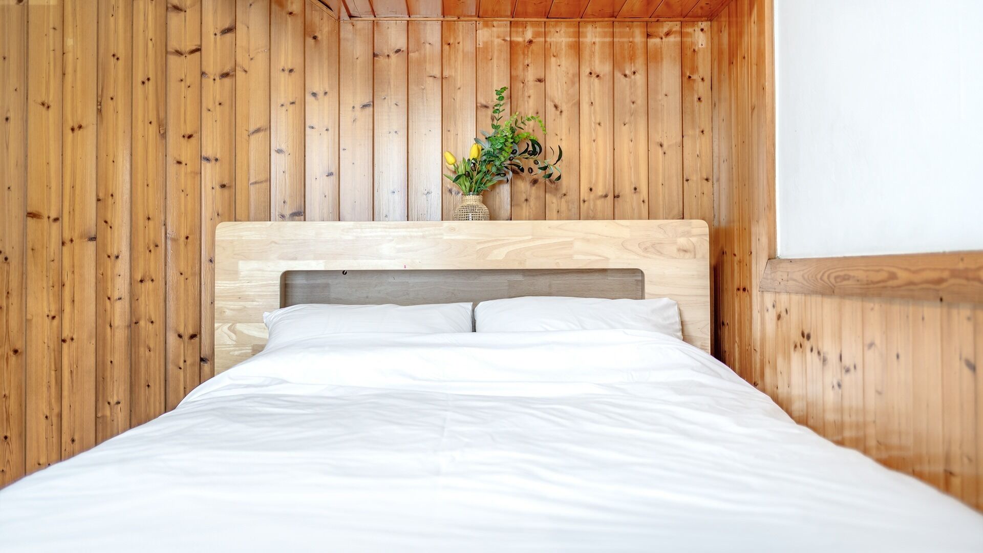 A bed with a wooden headboard in a room with wooden walls.