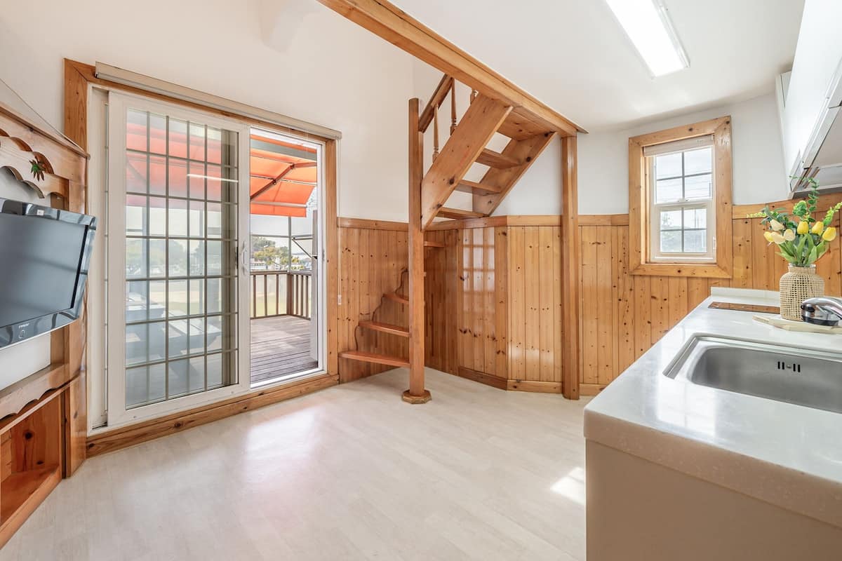 A modern kitchen with wooden accents, a built-in TV, and a large window.