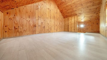 Een ruime zolderkamer met houten wanden en een schuin plafond.