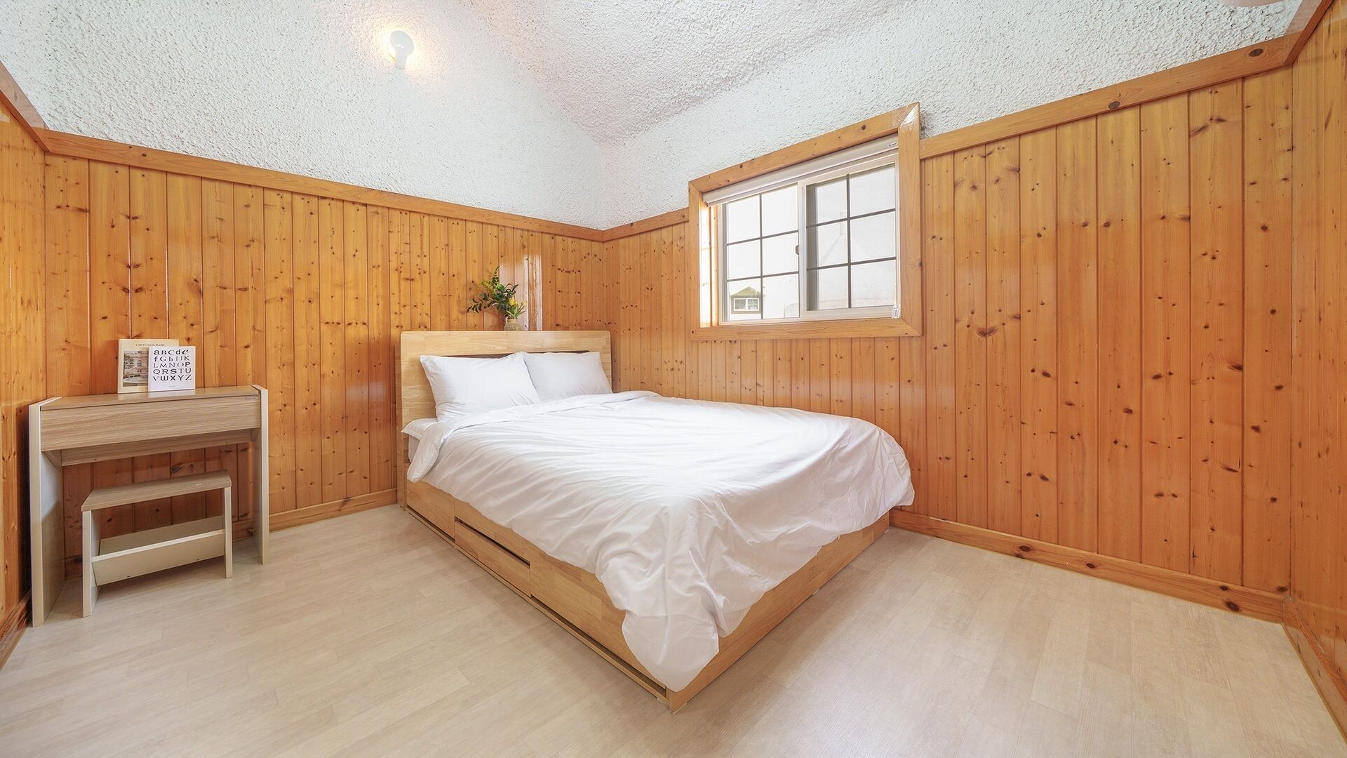 A bedroom with a wooden bed, a nightstand, a window, and a ceiling light.