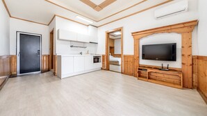 A spacious room with a kitchenette, a television, and a door leading to another room. - Daebudo Sketch Pension (Ansan)