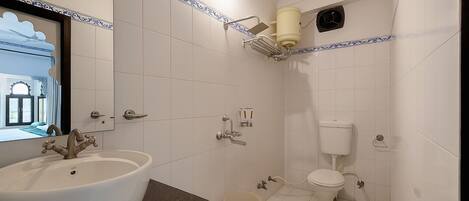 A bathroom with a large sink, toilet, and shower.