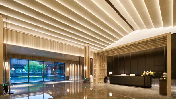 A modern lobby with a reflective floor, a reception desk, and a large glass wall offering a view of greenery. - ningbo narada estate (Ningbo)