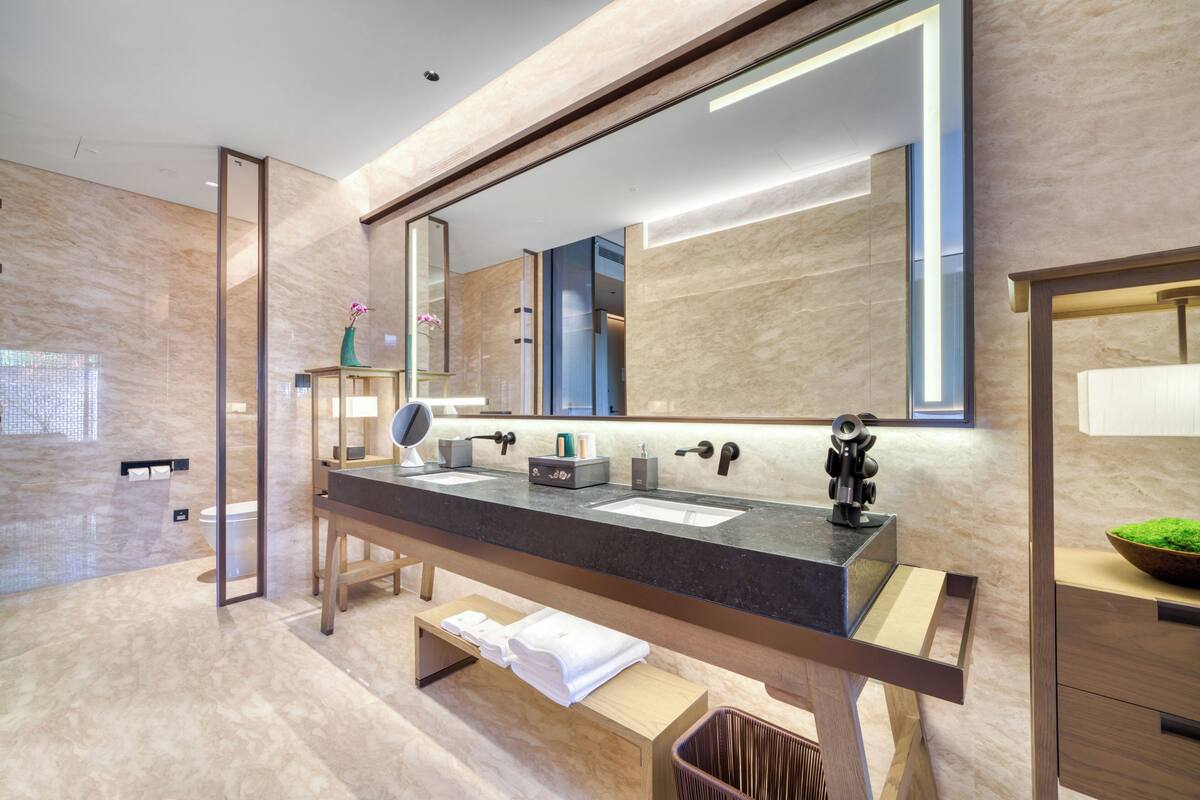 A modern bathroom with a large mirror, two sinks, and a vanity with a mirror.
