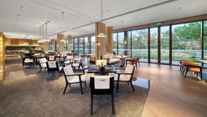 A spacious indoor area with multiple tables and chairs, large windows offering a view of greenery outside. - ningbo narada estate (Ningbo)