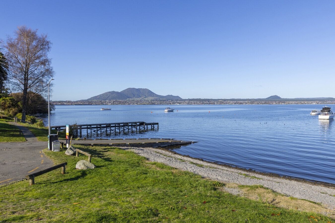 Vista al agua con muelle, barcos y una montaña al fondo.