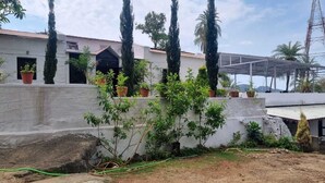 Un quartiere residenziale con un edificio bianco, piante in vaso e uno spazio esterno coperto.