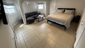A bedroom with a bed, a sofa, a coffee table, and a window. - Keel at Soundview · Beach+OceanView+Sunrise (Old Lyme)