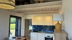 A modern kitchen with white cabinets, a blue backsplash, and a hanging light fixture.