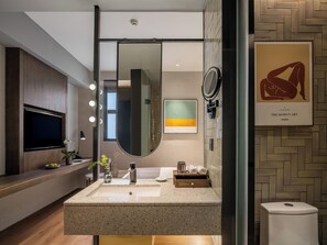 A modern bathroom with a large mirror, vanity, and a television. - Yat hotel (Guangzhou)