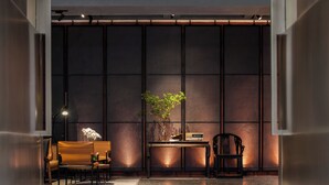 A modern interior with a seating area, a table with a plant, and a large window with a view.