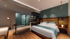 A modern hotel room with a large bed, bedside tables, a desk, and a mirror.
